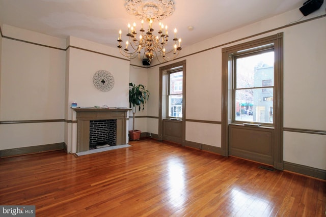 unfurnished living room featuring hardwood / wood-style flooring, a healthy amount of sunlight, and an inviting chandelier