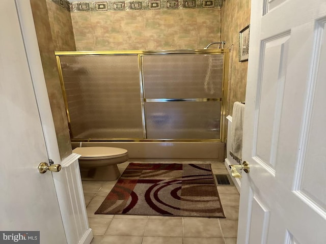 bathroom featuring toilet, tile patterned flooring, and combined bath / shower with glass door