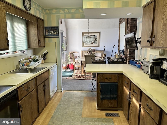 kitchen featuring dishwasher, black electric range oven, sink, light hardwood / wood-style flooring, and decorative light fixtures