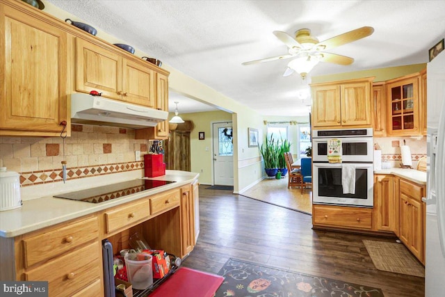 kitchen with ceiling fan, dark hardwood / wood-style floors, double oven, black electric cooktop, and decorative backsplash