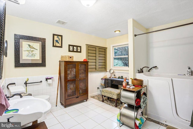 bathroom featuring tile patterned floors, a bath, sink, and a textured ceiling