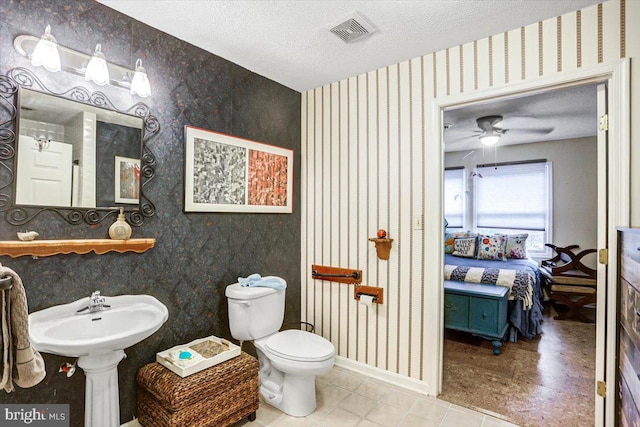 bathroom featuring ceiling fan, toilet, and a textured ceiling