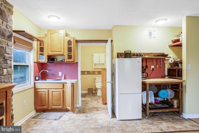 kitchen with tasteful backsplash, sink, and white refrigerator