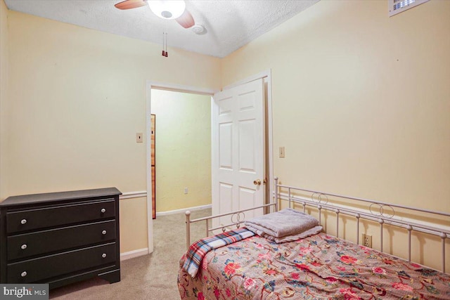 bedroom featuring ceiling fan, light colored carpet, and a textured ceiling