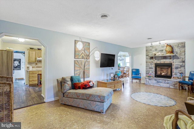 living room with a textured ceiling and a fireplace