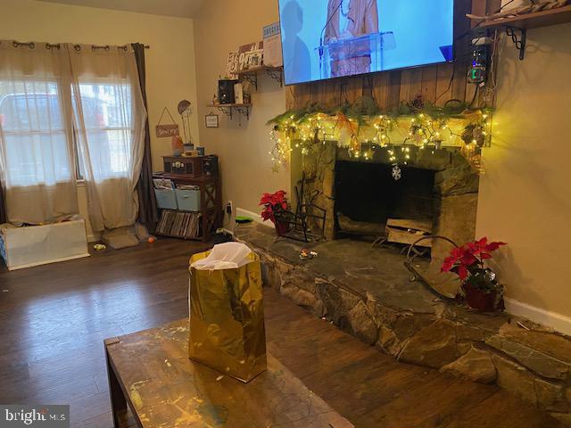 dining room featuring a stone fireplace and dark hardwood / wood-style floors