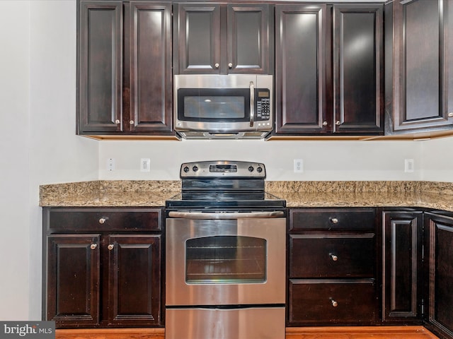 kitchen featuring dark brown cabinets, light stone countertops, and stainless steel appliances