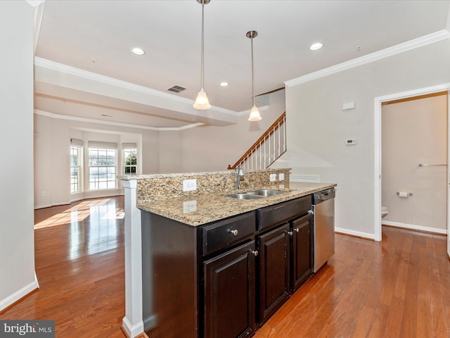 kitchen featuring stainless steel dishwasher, dark brown cabinets, a kitchen island with sink, sink, and light hardwood / wood-style flooring