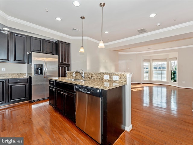 kitchen featuring decorative light fixtures, stainless steel appliances, crown molding, and sink