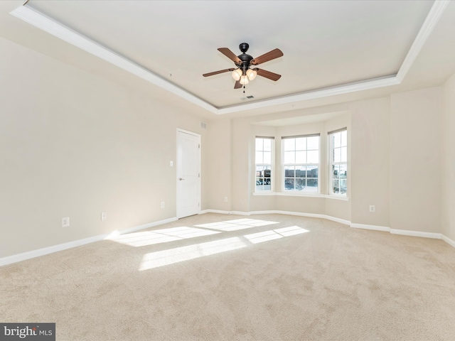 carpeted empty room featuring a tray ceiling, ceiling fan, and ornamental molding