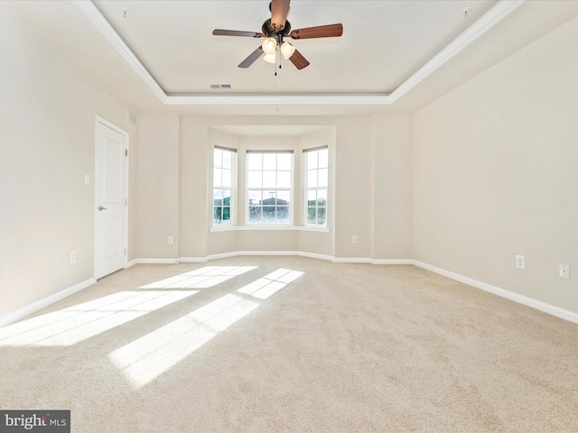 carpeted empty room featuring a tray ceiling, ceiling fan, and ornamental molding