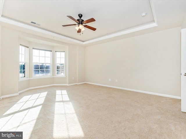 carpeted spare room with ceiling fan and a tray ceiling