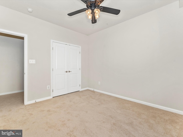 unfurnished bedroom featuring ceiling fan, light colored carpet, and a closet