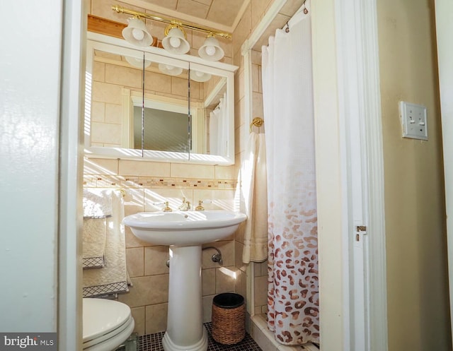 bathroom featuring toilet, a shower with shower curtain, and tile walls