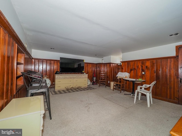 carpeted living room featuring wood walls