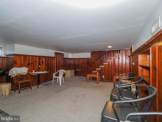 living area featuring light colored carpet and wood walls