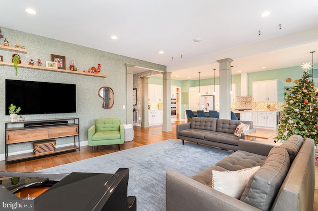 living room featuring light wood-type flooring and decorative columns