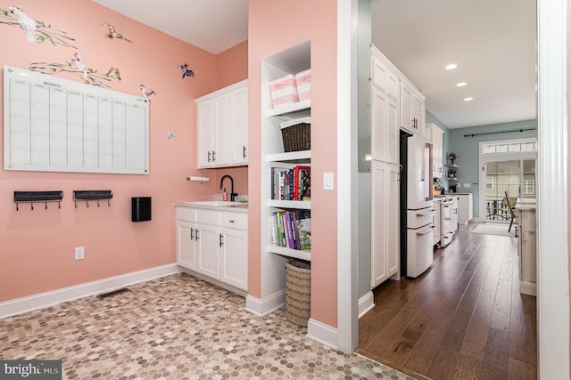 kitchen featuring hardwood / wood-style floors, high end white fridge, white cabinetry, and sink