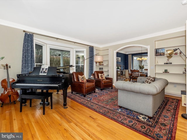 living room with wood-type flooring, an inviting chandelier, and ornamental molding