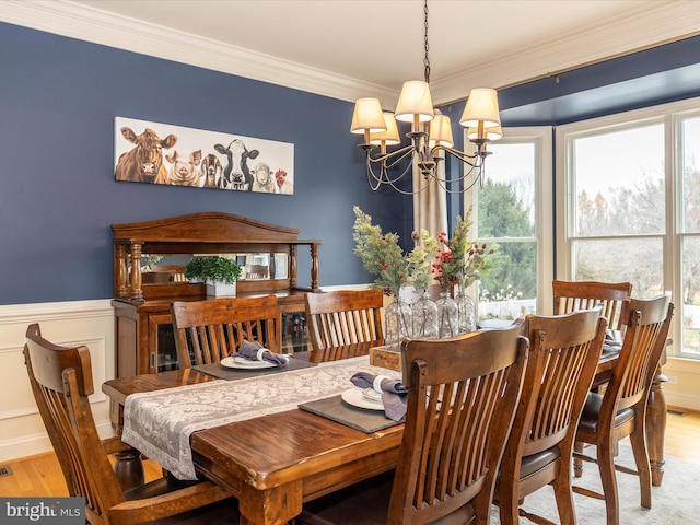 dining area with ornamental molding, light wood-type flooring, and a notable chandelier