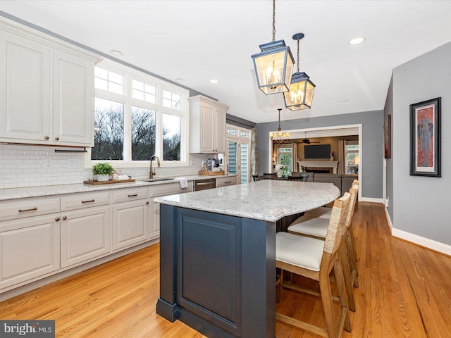 kitchen with pendant lighting, a center island, tasteful backsplash, and light hardwood / wood-style flooring