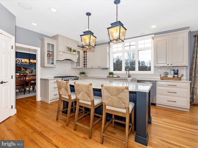 kitchen with stainless steel dishwasher, a center island, backsplash, and light hardwood / wood-style flooring