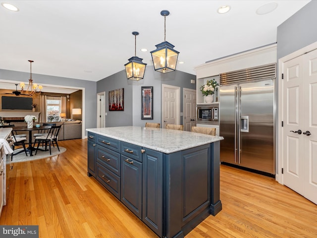 kitchen featuring blue cabinetry, built in appliances, light wood-type flooring, and an inviting chandelier