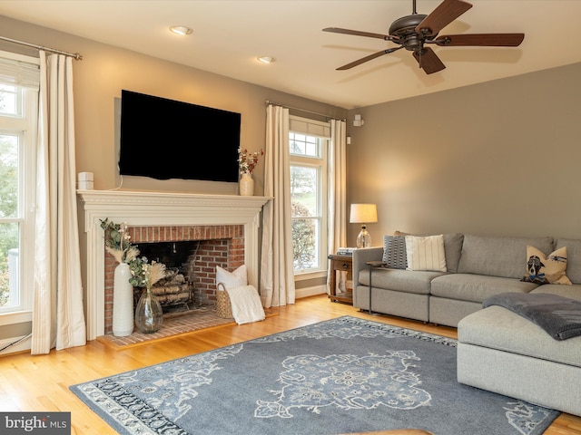 living room featuring ceiling fan, wood-type flooring, and a fireplace