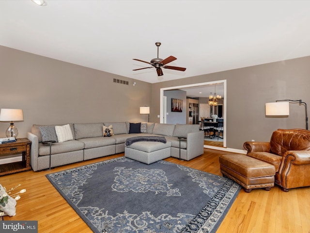 living room with hardwood / wood-style floors and ceiling fan with notable chandelier