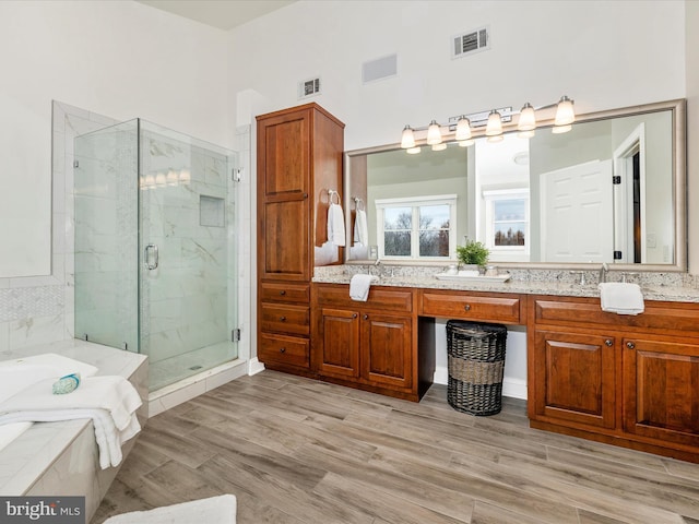 bathroom with hardwood / wood-style floors, vanity, and shower with separate bathtub