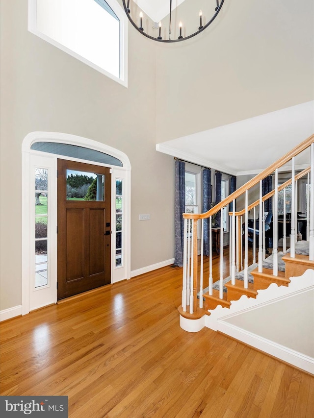 foyer entrance with hardwood / wood-style floors, a towering ceiling, and plenty of natural light