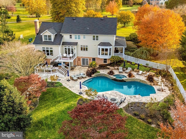 rear view of property featuring outdoor lounge area, a yard, a patio, and a pool with hot tub