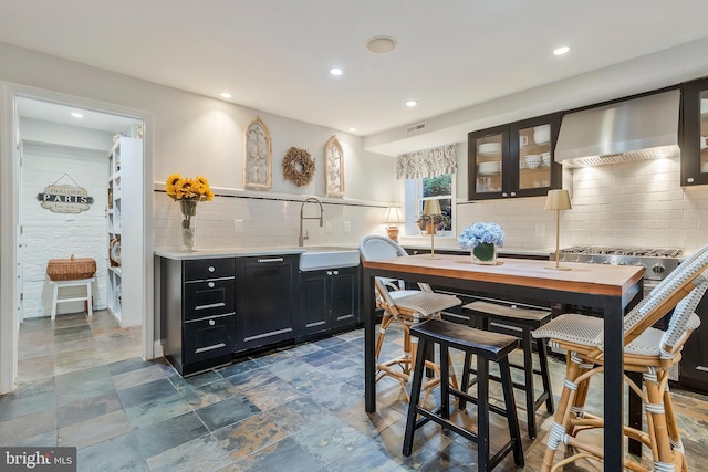 kitchen featuring decorative backsplash, stainless steel gas cooktop, wall chimney exhaust hood, and sink