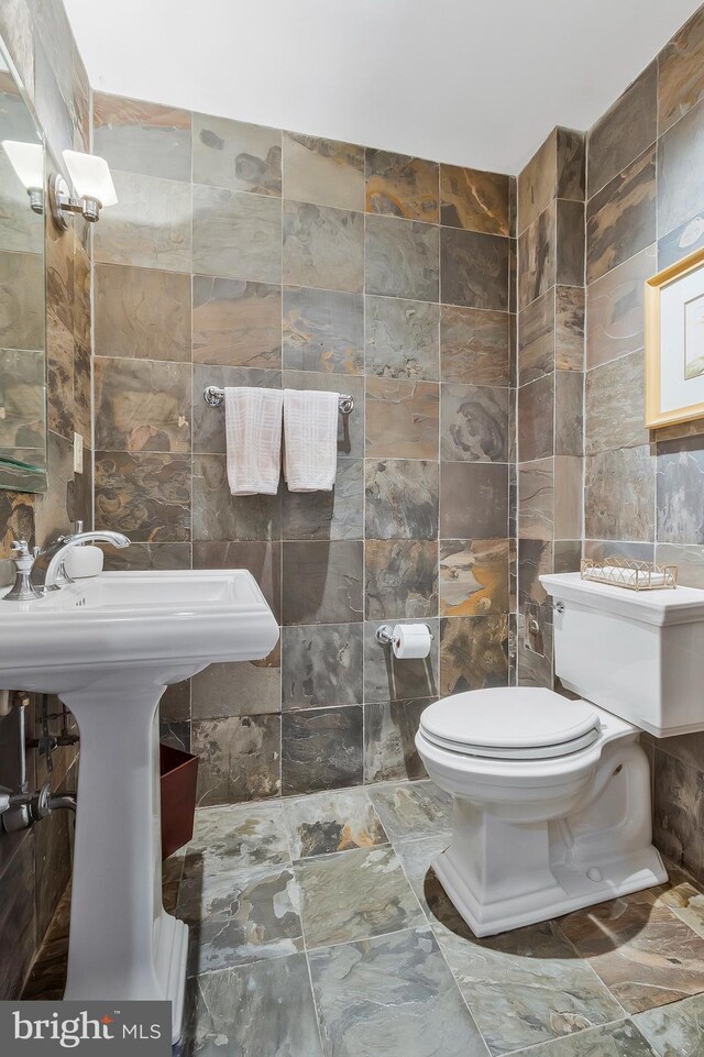 bathroom featuring toilet and tile walls