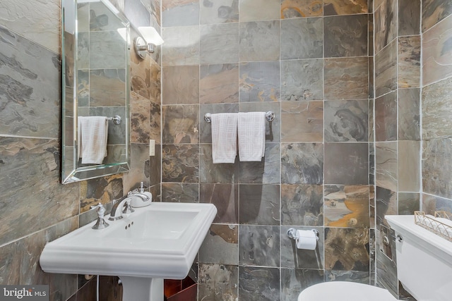 bathroom with sink, tile walls, and toilet