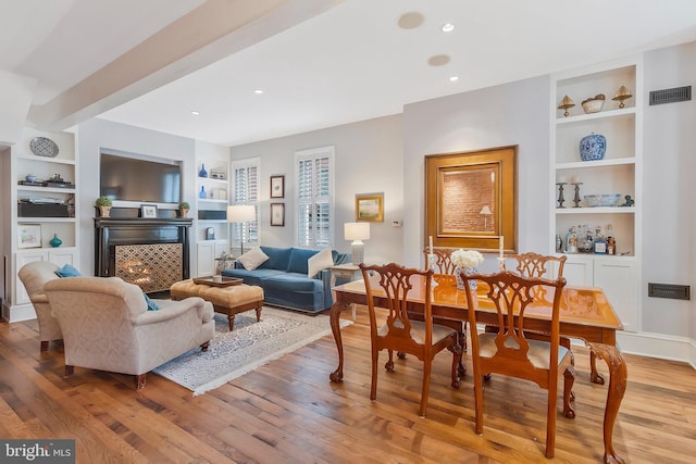 living room featuring built in shelves and light wood-type flooring