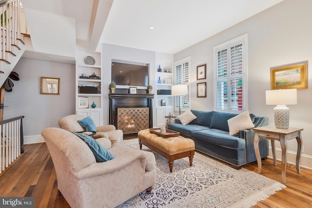 living room featuring built in shelves and light hardwood / wood-style floors