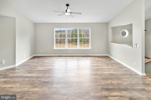 empty room with ceiling fan, wood-type flooring, and vaulted ceiling