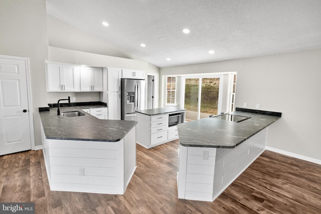 kitchen featuring stainless steel fridge, kitchen peninsula, white cabinetry, and sink