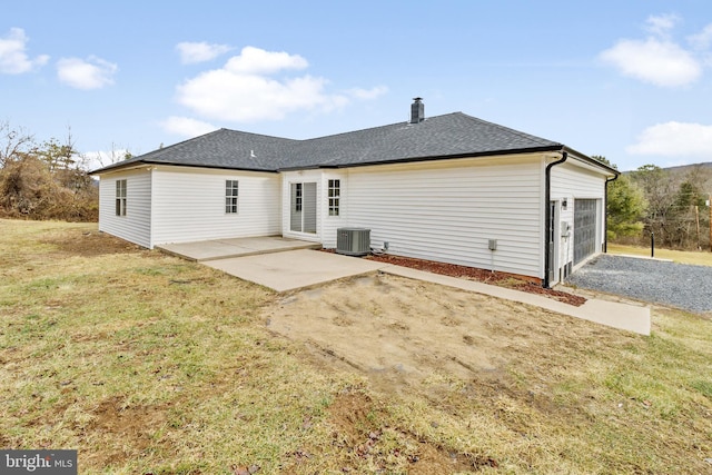 back of property with central AC, a yard, a garage, and a patio area