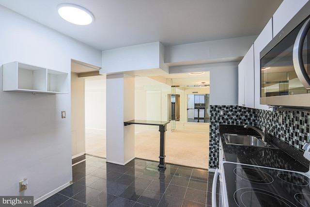 kitchen with backsplash, range with electric cooktop, sink, and dark colored carpet