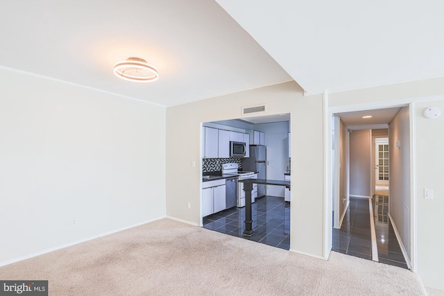 interior space featuring stainless steel appliances, dark carpet, and tasteful backsplash