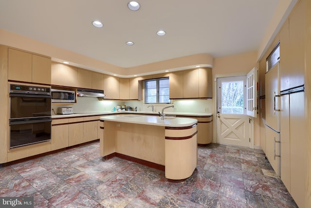 kitchen with double oven, a wealth of natural light, a center island with sink, and stainless steel microwave