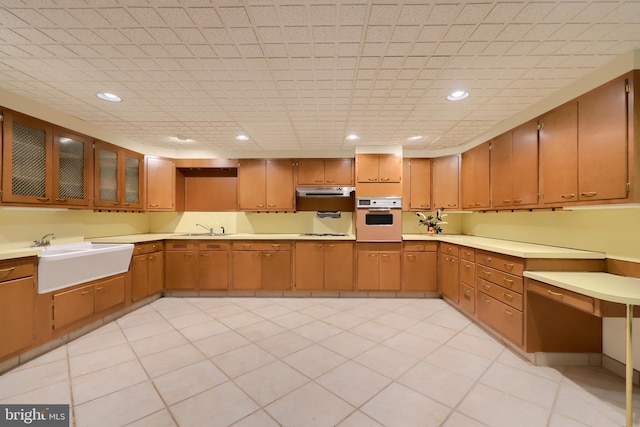 kitchen featuring white oven, sink, light tile patterned flooring, and stovetop