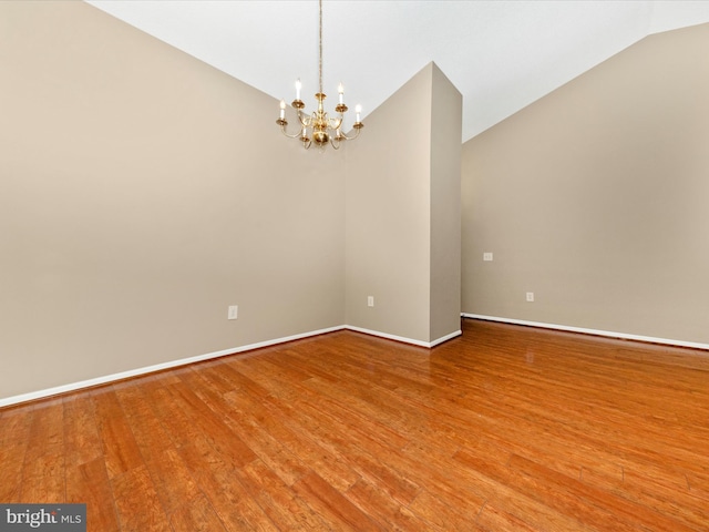 unfurnished room featuring wood-type flooring, lofted ceiling, and an inviting chandelier