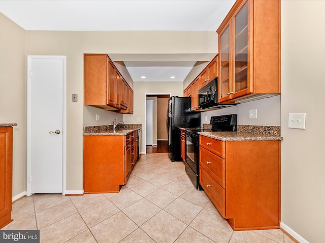 kitchen featuring light tile patterned floors, sink, light stone counters, and black appliances