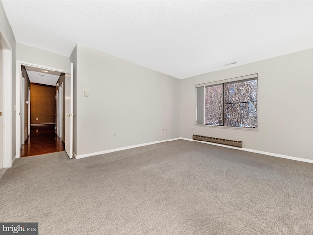 carpeted spare room with a baseboard heating unit