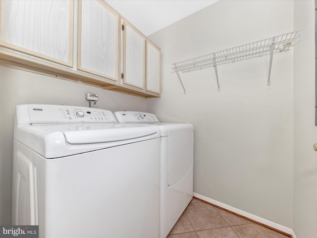 clothes washing area with washer and clothes dryer, light tile patterned flooring, and cabinets