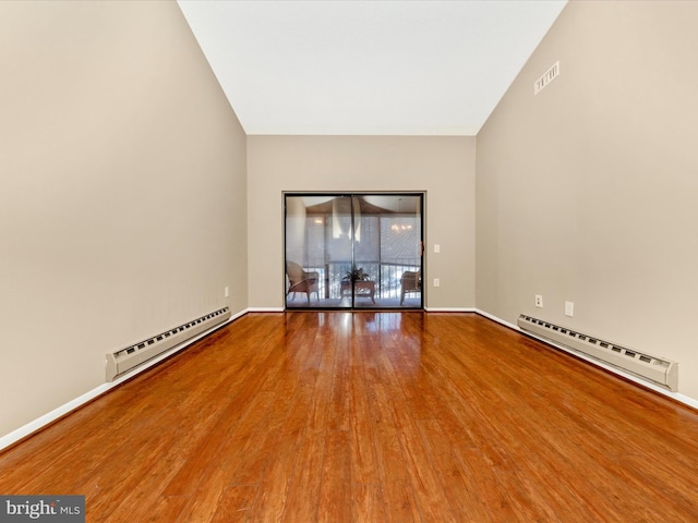 spare room featuring wood-type flooring and baseboard heating