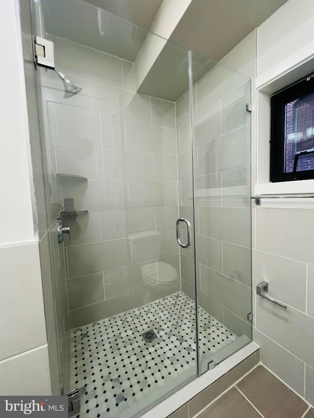 bathroom with a shower with door and toilet